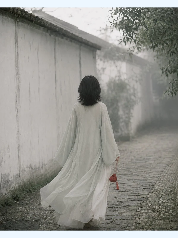 Adult figure in a long robe walking through a rainy Jiangnan alley